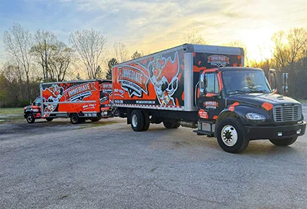 Two Immediate Movers & Storage trucks parked in a lot at sunrise.