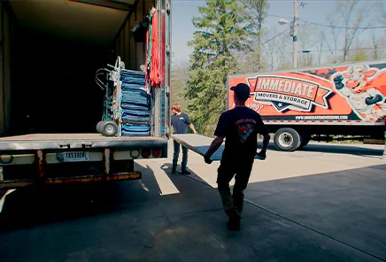 A mover walks up the loading ramp of an Immediate Movers truck.