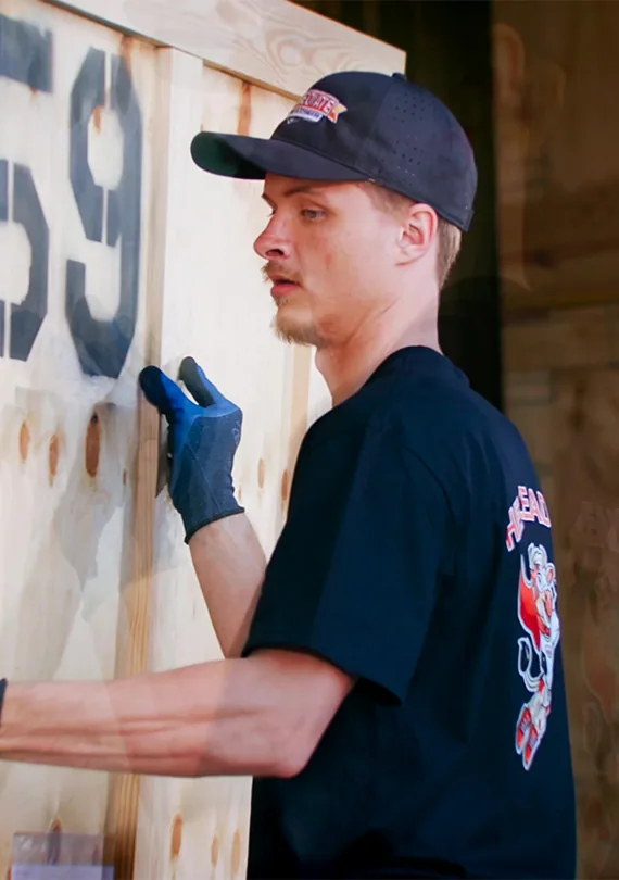 A mover in a cap and gloves secures a wooden storage vault.